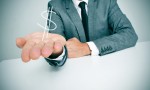 Wie geht man mit Investoren um? (Foto: Shutterstock - http://www.shutterstock.com/pic-172819604/stock-photo-a-businessman-sitting-in-a-desk-showing-a-drawn-dollar-sign-in-his-hand.html)